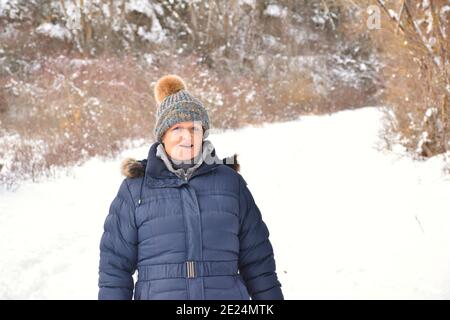 Pensionierte Frau mit bunten Jacke und Hut in ländlicher Umgebung mit Schnee. Szene nach dem Schneesturm namens Filomena in Spanien. Januar 2021. Stockfoto