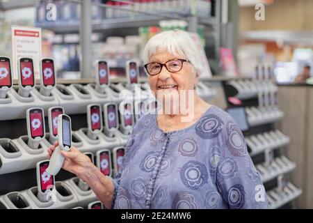 Lächelnde Frau hält Barcodeleser im Supermarkt Stockfoto