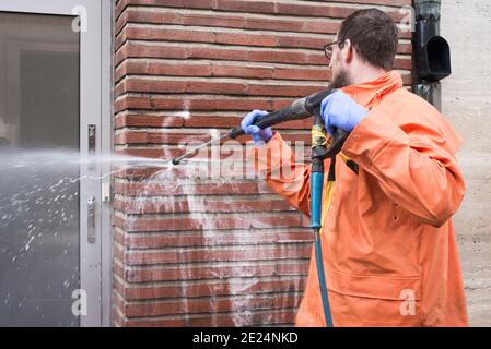 Mann, der Graffiti von der Wand putzt Stockfoto