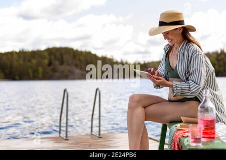 Frau auf dem Steg beim Betrachen des digitalen Tablets Stockfoto