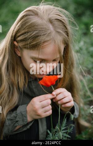 Porträt eines Mädchens, das auf einem Feld steht, das einen Mohnrochen riecht, Russland Stockfoto