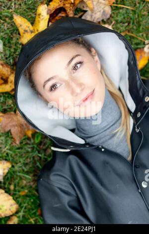 Junge Frau liegt auf Blätter im Herbst Stockfoto