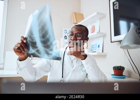 Ein überlegtes Arzt evaluiert die Röntgenaufnahme des Brustkorbs Stockfoto