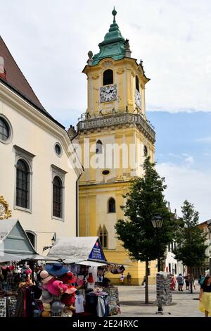 Bratislava, Slowakei - 21. Juli 2019: Nicht identifizierte Menschen und Straßenmarkt mit zugänglicher Turm des alten Rathauses und Jesuitenkirche Stockfoto