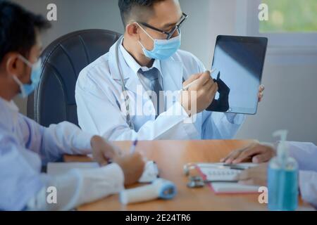 Drei Ärzte sitzen in einem Büro mit einer Sitzung, Thailand Stockfoto