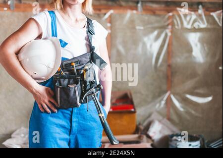 Frau Baumeister in Overalls mit Werkzeug und Hut Stockfoto