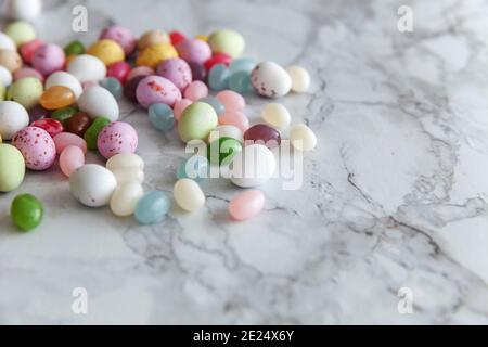 Frohes Osterkonzept. Vorbereitung für den Urlaub. Schokoladeneier aus Osterkerbonbons und Quallen auf dem trendigen grauen Marmorhintergrund. Einfacher Minimalismus fl Stockfoto