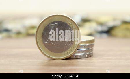Nahaufnahme einer Euro-Münze auf dem Desktop. Europäisches metallisches Bargeld und im Hintergrund Eurocent-Münzen sind nicht im Fokus Stockfoto