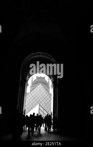 Menschen und Kunst. Silhouetten von Touristen, die durch den Durchgang zur Pyramide des Louvre gehen. Schwarz weiß historische konzeptionelle Foto Stockfoto