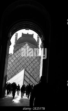 Menschen und Kunst. Silhouetten von Touristen, die durch den Durchgang zur Pyramide des Louvre gehen. Schwarz weiß historische konzeptionelle Foto Stockfoto