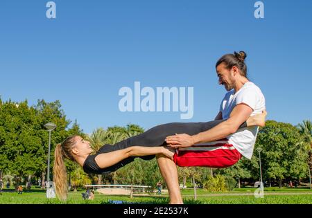 Glückliches Paar Mit Spaß Suchen Einander Üben Acro Yoga Pose im Park am Valentinstag Stockfoto