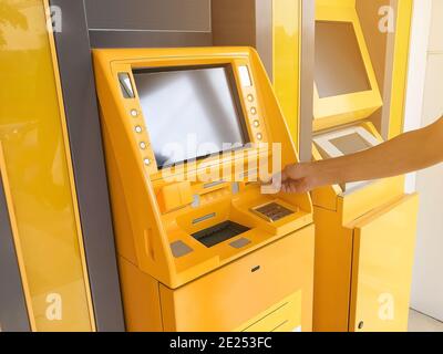 Man's Hand steckt eine ATM-Karte in einem Bankautomaten. Stockfoto