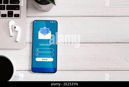Geschäftsmarketing. Smartphone mit Newsletter-Anmeldeformular auf dem Bildschirm liegend auf dem Tisch Stockfoto