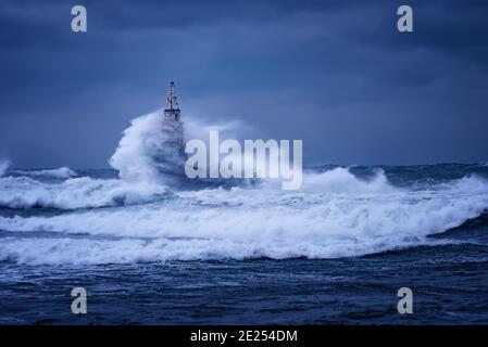 Große Welle gegen den alten Leuchtturm im Hafen von Ahtopol, Schwarzes Meer, Bulgarien an einem stürmischen Tag. Gefahr, dramatische Szene. Stockfoto