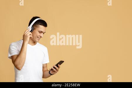 Moderne App für Songs und Audio. Lächelnder Millennial-Mann in Kopfhörern hört Lieblingsmusik Stockfoto