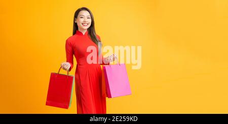 Fröhliche junge Frau trägt AO dai Kleid halten Einkaufstaschen Stockfoto