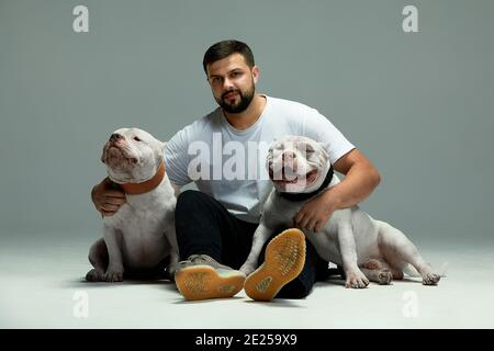Schöner Mann und ein charmanter Hund schikaniert. Nahaufnahme, drinnen. Studio Foto, weiß. Konzept der Pflege, Bildung, Gehorsam Ausbildung und Erziehung von Haustieren Stockfoto