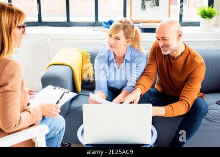 Glückliches Paar, das mit ihrer Geschäftsfrau des Finanzberaters kommunizierte, während es zu Hause im Wohnzimmer saß. Stockfoto