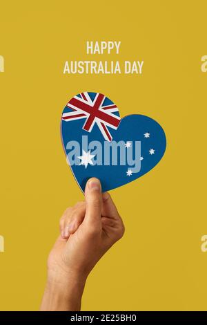 Nahaufnahme der Hand eines Mannes mit einer australischen Flagge in Form eines Herzens, mit Ausschnitten aus Papier in verschiedenen Farben, und der Text glücklich au Stockfoto