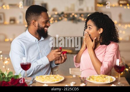 Junger schwarzer Mann macht Vorschlag mit Ring zu seiner Frau Stockfoto