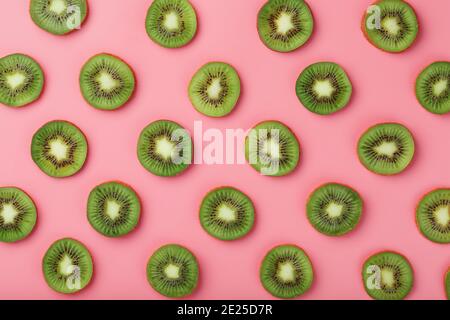 Reife Kiwi Scheiben in Mustern auf einem rosa Hintergrund. Draufsicht Vollbild Stockfoto