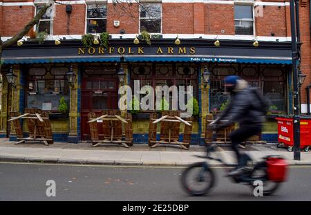 Ein Radfahrer fährt während der nationalen Coronavirus-Sperre in England an einem geschlossenen Pub in Central London vorbei. Stockfoto