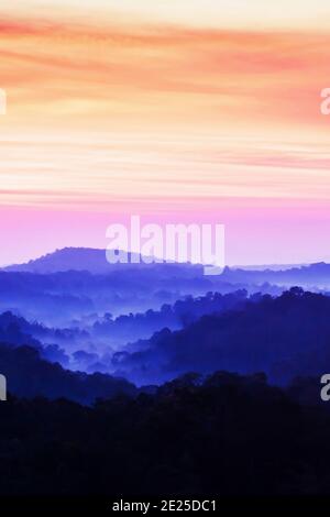 Herrliche Wolkenlandschaft über blauen Bergen im Morgennebel, hellrosa Wolken gegen blaue Berge im Nebel. Nam Nao Nationalpark, Thailand. Stockfoto