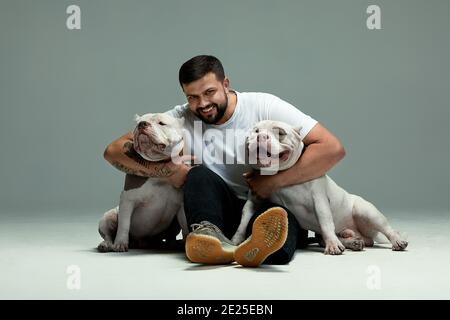 Schöner Mann und ein charmanter Hund schikaniert. Nahaufnahme, drinnen. Studio Foto, weiß. Konzept der Pflege, Bildung, Gehorsam Ausbildung und Erziehung von Haustieren Stockfoto