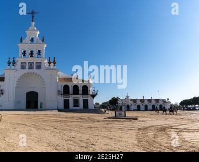 El Rocio, Spanien - 9. Januar 2021: Kirche Ermita de Rocio und Stadtplatz mit Pferden und Reitern Stockfoto