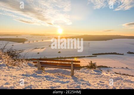 Malerischer Sonnenuntergang über schöner Winterlandschaft im Schwäbischen Alpen mit Bank im Vordergrund Stockfoto