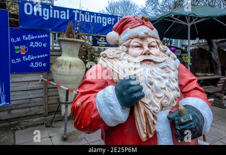 Boltenhagen, Deutschland. Dezember 2020. Die Figur eines Weihnachtsmannes steht vor einem geschlossenen Restaurantbereich an der Strandpromenade. Aufgrund der teilweisen Corona-Sperre sind Hotels, Restaurants und touristische Einrichtungen an der Ostseeküste in Mecklenburg-Vorpommern geschlossen. Quelle: Jens Büttner/dpa-Zentralbild/ZB/dpa/Alamy Live News Stockfoto