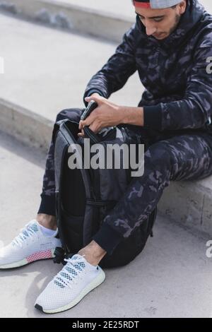 Vertikale Aufnahme eines jungen Mannes, der sich mit einem vorbereitet Rucksack zum draußen trainieren Stockfoto