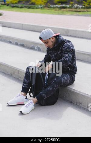 Vertikale Aufnahme eines jungen Mannes, der sich mit einem vorbereitet Rucksack zum draußen trainieren Stockfoto