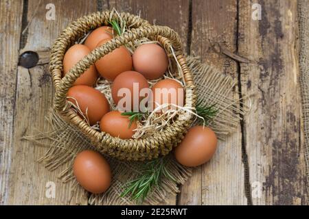 Eier in einem Korb auf Holzhintergrund Stockfoto