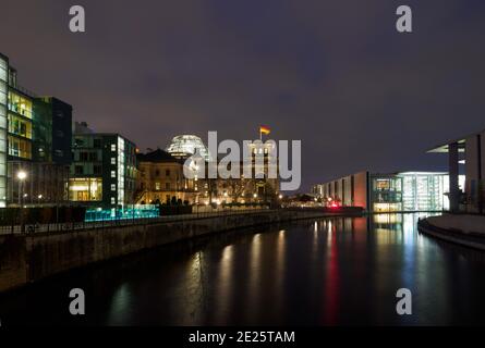 Berlin, Deutschland. Januar 2021. Die Lichter der Straßenbeleuchtung am Reichstagsufer, am Reichstag und am Paul-Löbe-Haus (r) spiegeln sich abends an der Wasseroberfläche der Spree. Quelle: Soeren Stache/dpa-Zentralbild/ZB/dpa/Alamy Live News Stockfoto