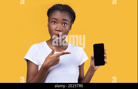 Schockierte Afrikanische Frau Zeigt Telefon Leer Bildschirm Auf Gelbem Hintergrund Stockfoto