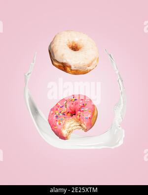 Zwei Donuts Donuts fallen in einen Spritzer Milch auf einem rosa Hintergrund mit Kopieplatz und Platz für Text. Stockfoto