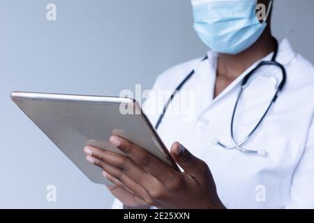Mischrasse weibliche Arzt trägt Gesichtsmaske stehen und mit Digitales Tablet Stockfoto