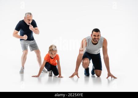 Reifer Mann pfeift in der Nähe von Vater und Sohn im Tiefstand Position auf Weiß Stockfoto