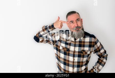 Hipster mit großem Bart und Schnurrbart im Retro-Stil und Karo-Shirt setzt den Zeigefinger seiner rechten Hand zu seinem Tempel, in klarem Gedankengut oder Stockfoto