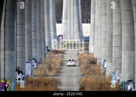 Weißes Auto unter massiver Betonbrücke Stockfoto