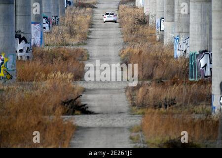 Weißes Auto unter massiver Betonbrücke Stockfoto