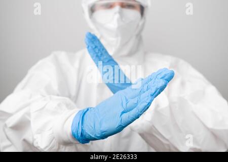 Arzt in einem biogefährlichen Schutzanzug und Schutzmaske bekämpft mit Coronavirus, SARS-Cov-2, Covid-19 in blauen Gummihandschuhen. Stockfoto