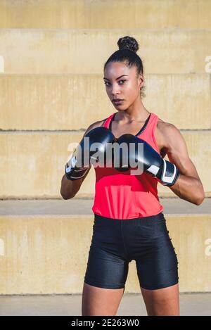 Vertikales Porträt einer afro-amerikanischen Athletin in schwarz Boxhandschuhe und in Verteidigungsposition stehen Stockfoto