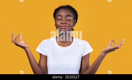 Friedliche Afrikanische Frau Meditiert Mit Geschlossenen Augen Auf Gelbem Hintergrund Stockfoto