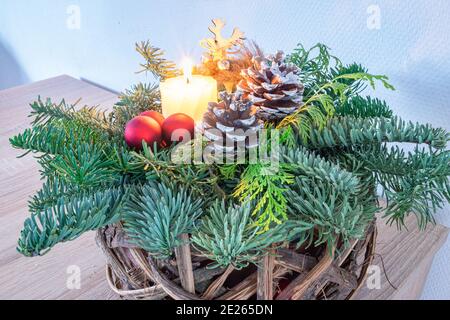 Weihnachtsdekoration mit Tannenzweigen, Tannenzapfen, Kugeln und brennender Kerze Stockfoto