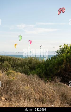 Viele Kitesurfer mit ihren Drachenschirmen in der Luft Am Strand von Tarifa Stockfoto