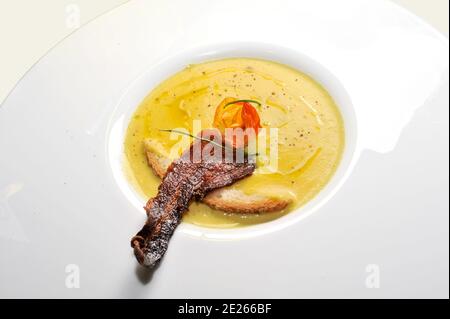 Käsefondue mit gebratenem Speck und Scheibe davon Brot auf weißem Teller Stockfoto