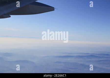 Fliegen über die Berge und das Meer mit Blick auf die rechte Seite Flugzeugflügel Stockfoto