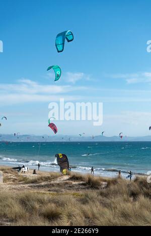 Viele Kitesurfer mit ihren Drachenschirmen in der Luft Am Strand von Tarifa Stockfoto